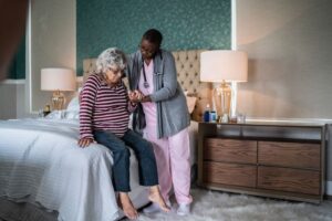 Nurse helping a senior woman standing in the bedroom